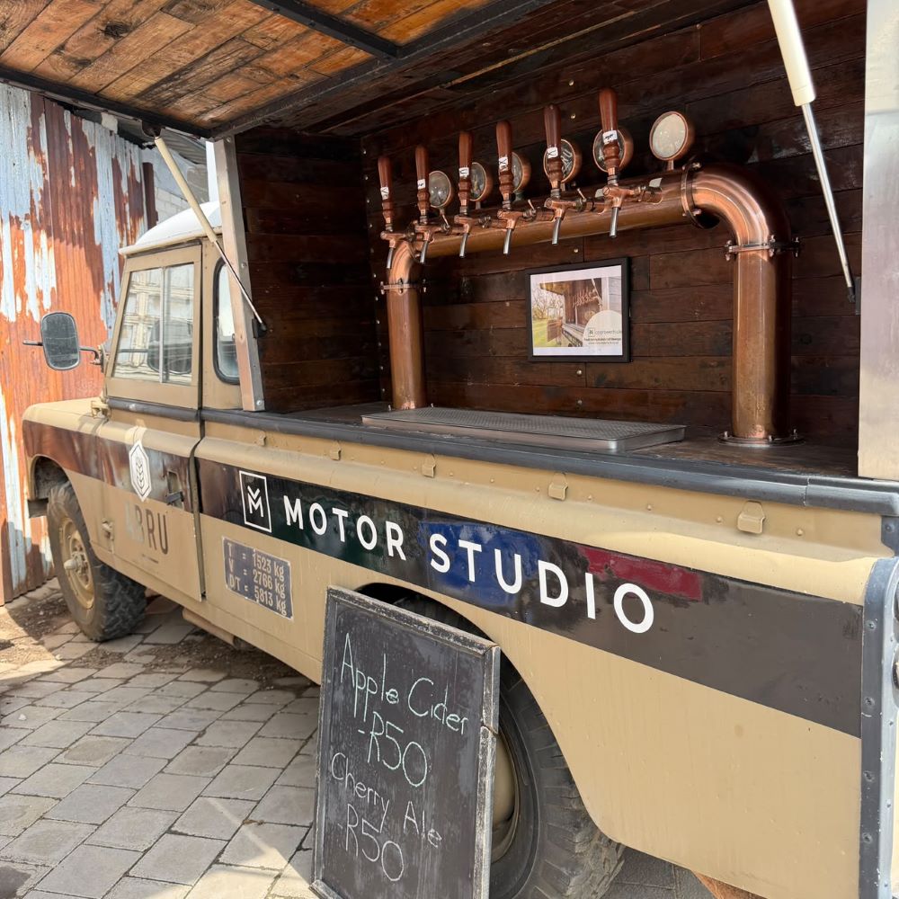 A custom mobile tap truck fitted with copper beer taps and a chalkboard menu displaying craft cider and ale during the club stop.