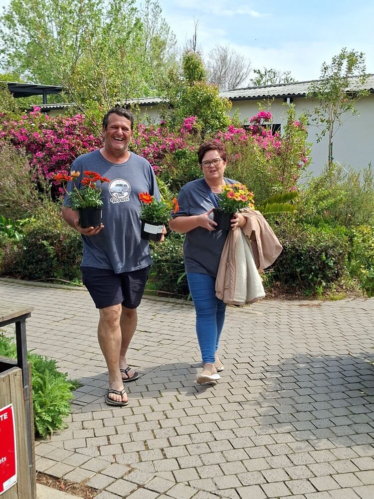 Club members holding potted flowering plants purchased during the garden and market stop on the club run.