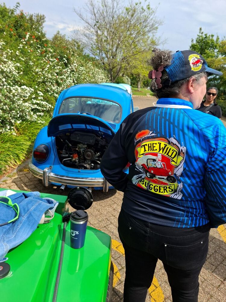 Mickey wearing club apparel while checking the engine compartment of a classic air-cooled VW before departure.
