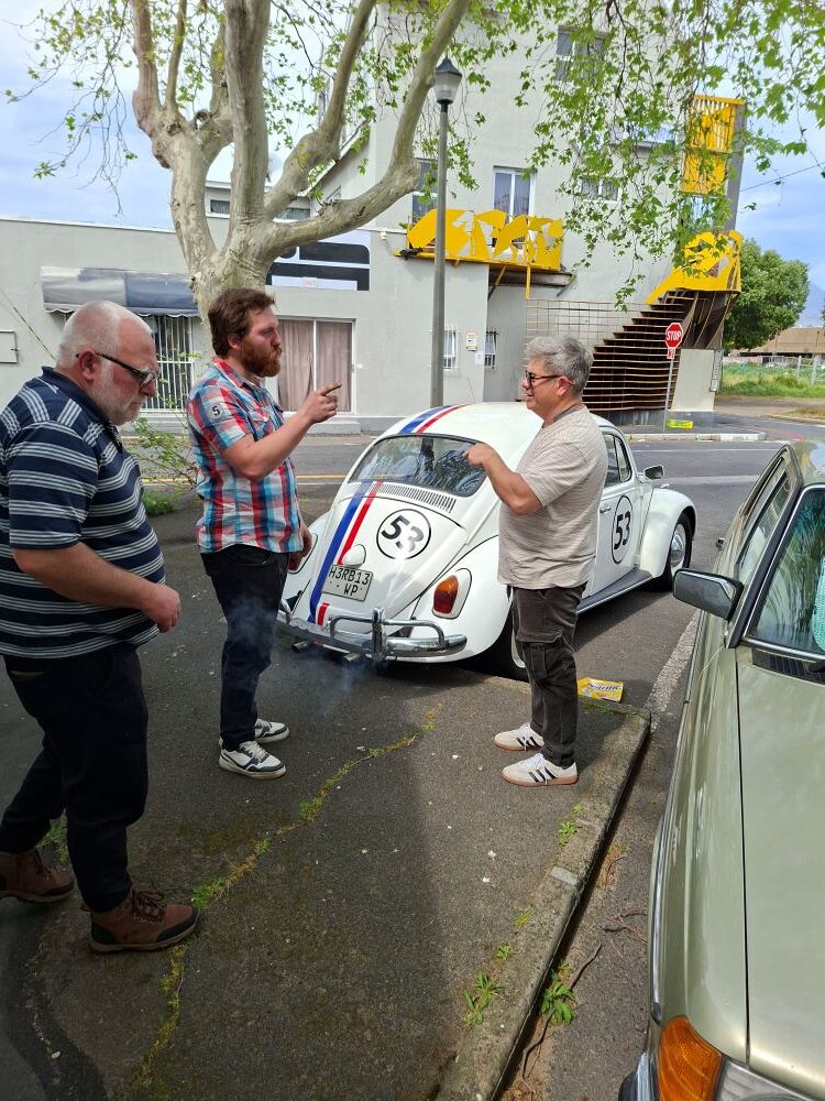 Bertus and Neil having a parking lot discussion next to a classic VW Beetle before heading into the Bacon Spot during the club run.