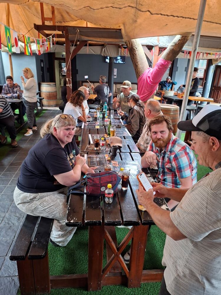 Club members chatting and having fun while waiting to order food together at a long wooden table during the stop.